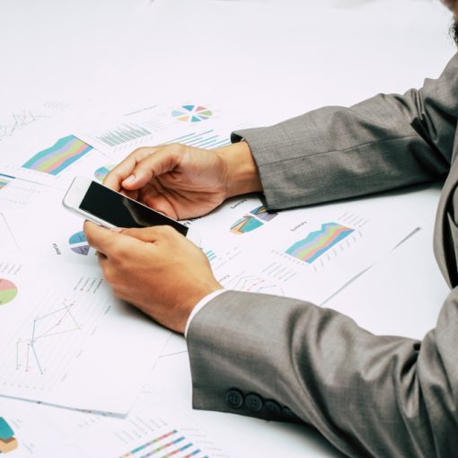 This is a picture of a businessman holding a mobile phone while analysing data