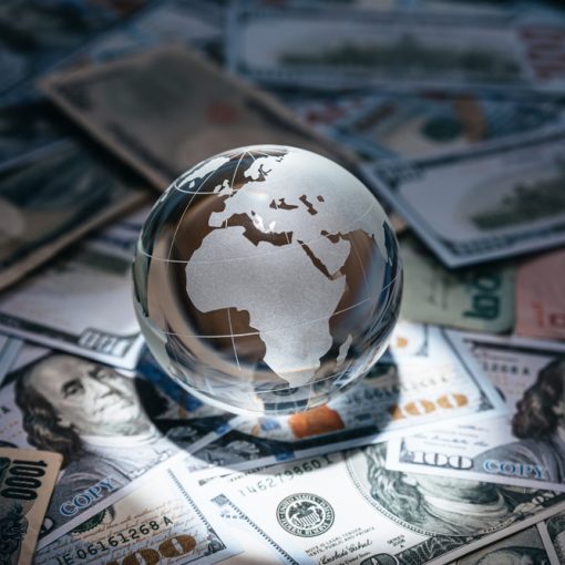 There is crystal globe resting on several currency notes from across the world