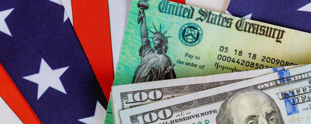 The picture shows US dollars and treasury bill in the backdrop of the flag