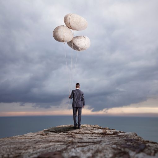 The image shows a businessman at the edge of a cliff