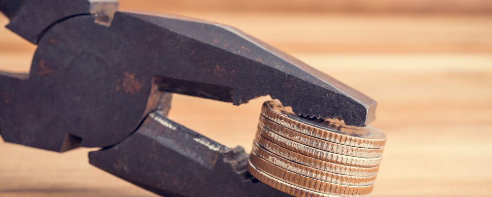 The image shows a plier tightening its grip on coins
