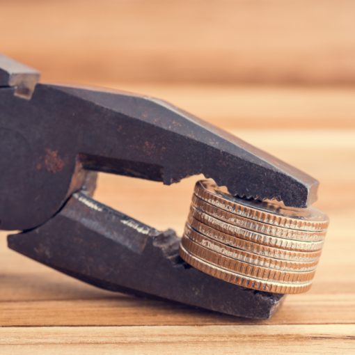 The image shows a plier tightening its grip on coins