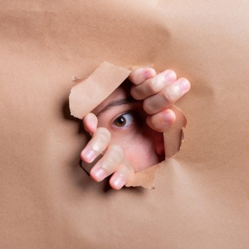The image shows an eye looking through a hole in paper