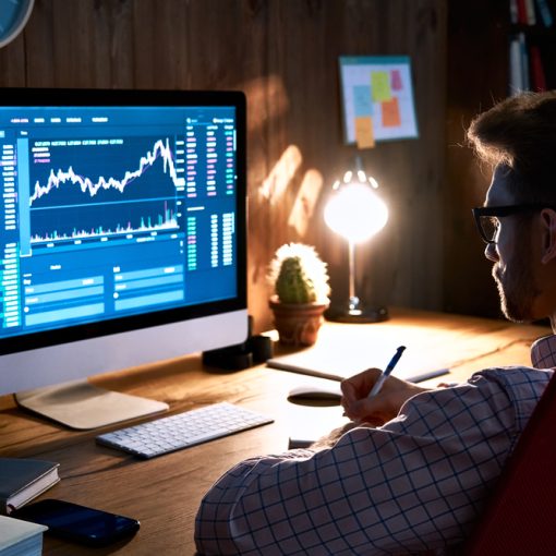 The image shows a man looking at market graphs on screen
