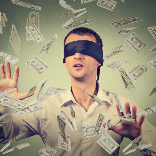 The image shows a businessman blindfolded amongst banknotes