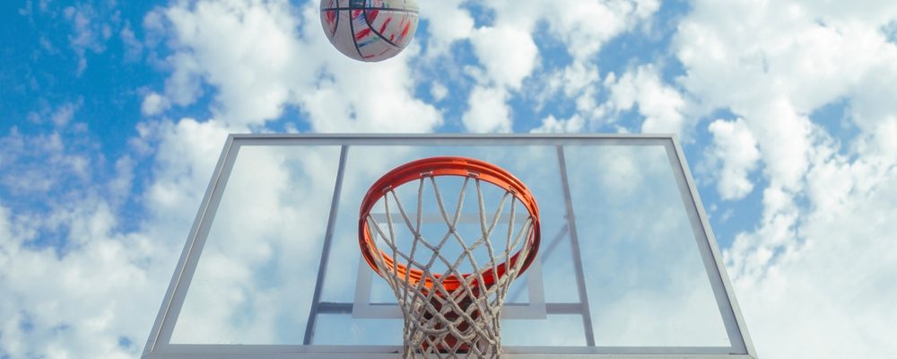 The image shows a basketball soaring towards hoops