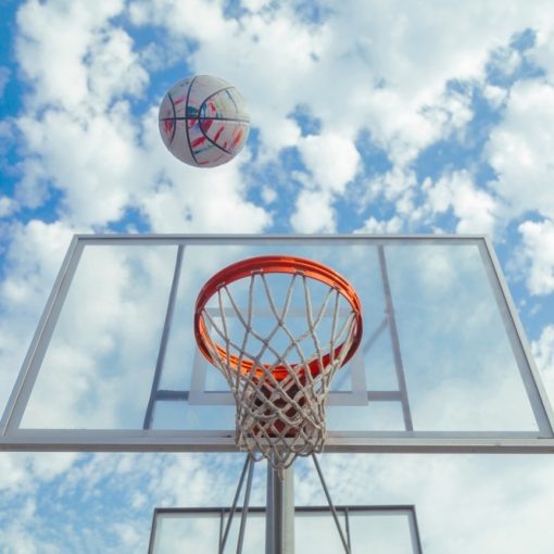 The image shows a basketball soaring towards hoops