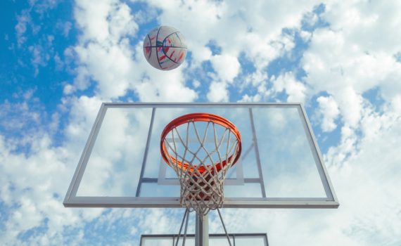 The image shows a basketball soaring towards hoops