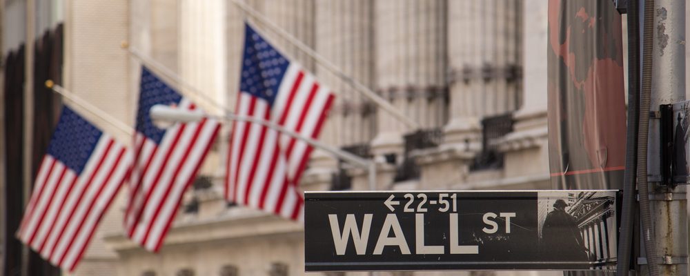 A wall street sign with US flags