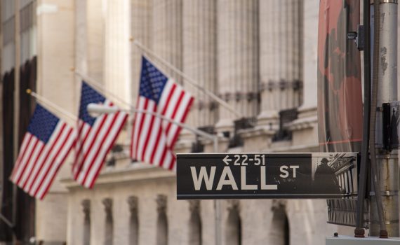 A wall street sign with US flags