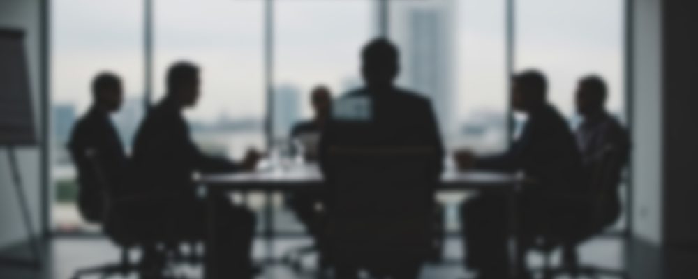 The image shows a worried group of businesspeople in discussion
