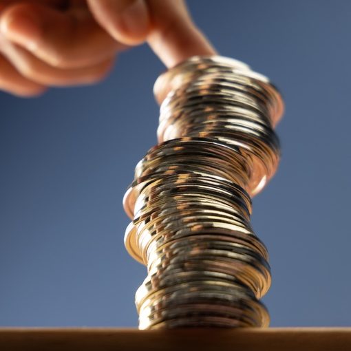 Hands Supporting Unstable Coin Stack
